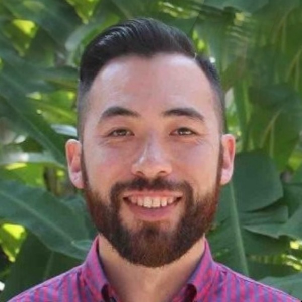 Man with brown hair and beard wearing a button down red and navy striped shirt.