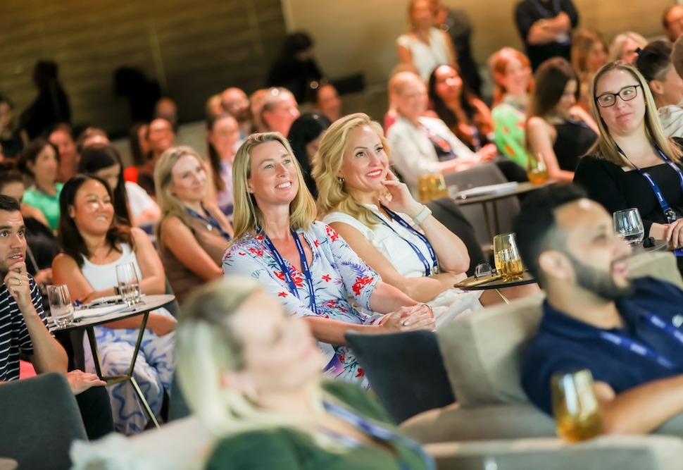 A crowd of happy professionals listening to an engaging talk at an event