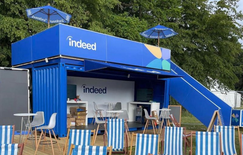 An outdoor event with colorful blue-and-white striped seating around an open booth.