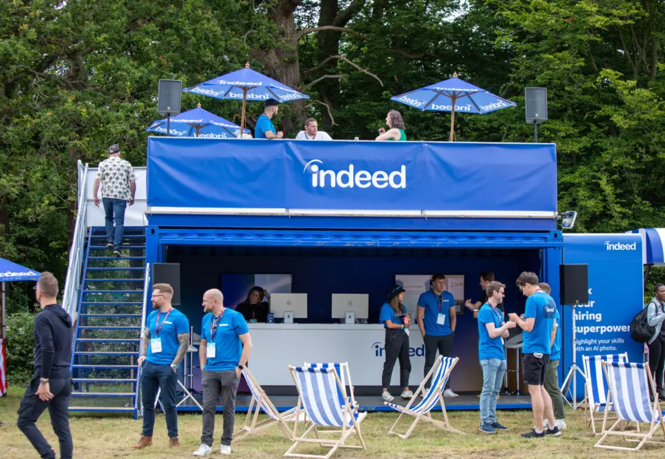 An outdoor event with colorful blue-and-white striped seating around an open booth.