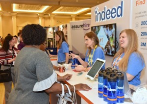 Asistentes que visitan un estand de feria comercial de Indeed