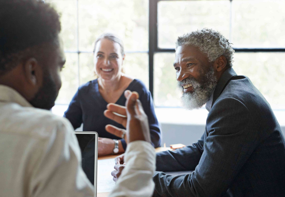 3 people (2 men and 1 woman) networking at a conference room table