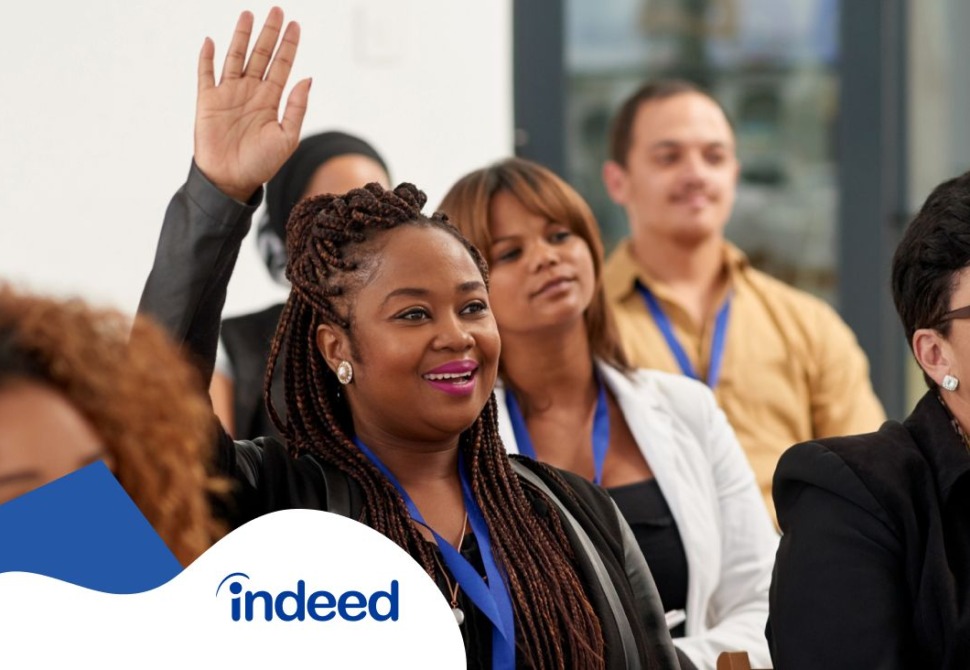 One black woman raising her hand to ask a question during a talking session