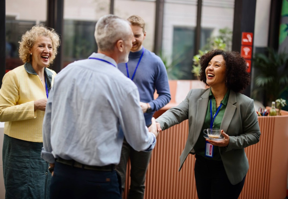 Two people greeting one another at a reception, two people in the background.