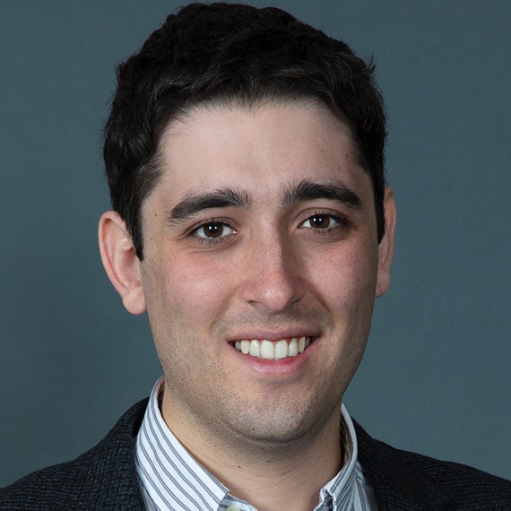 Headshot photo of Ezra Karger looking at the camera