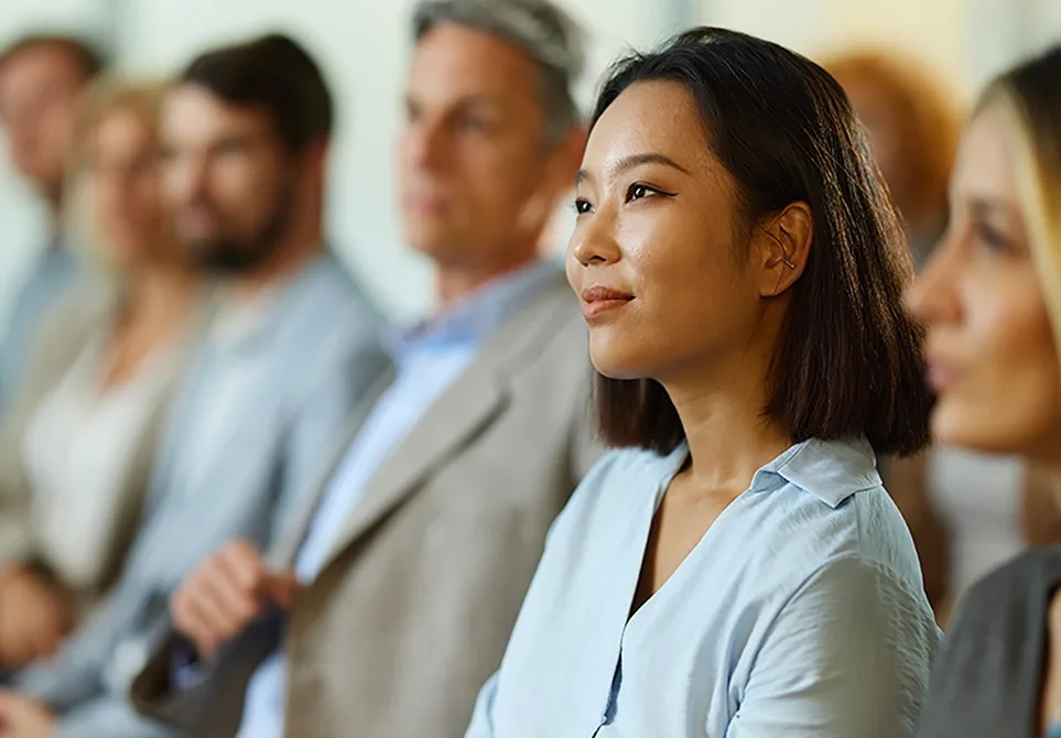A room full of leaders listening intently to somebody giving a presentation in an office conference room
